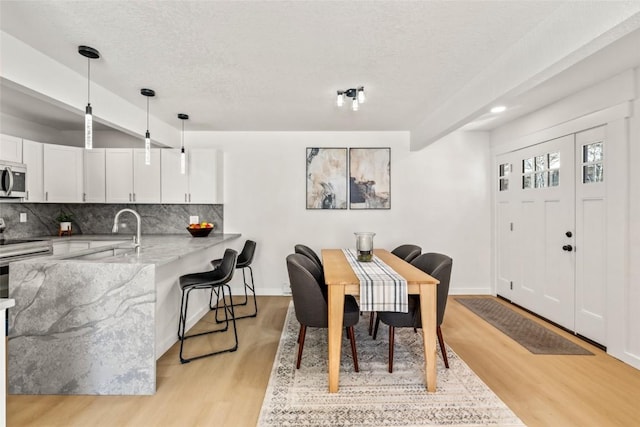 dining space featuring light wood-style floors, baseboards, and a textured ceiling