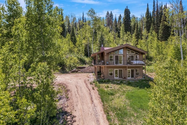 58195 Jupiter Pl, Clark, CO 80428 - view of front of home with dirt driveway, a forest view, a chimney, and a wooden deck