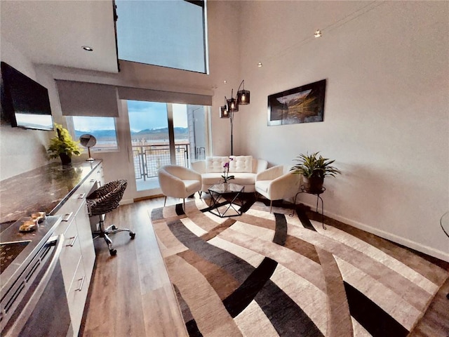 office space with light wood-style flooring, a towering ceiling, and baseboards
