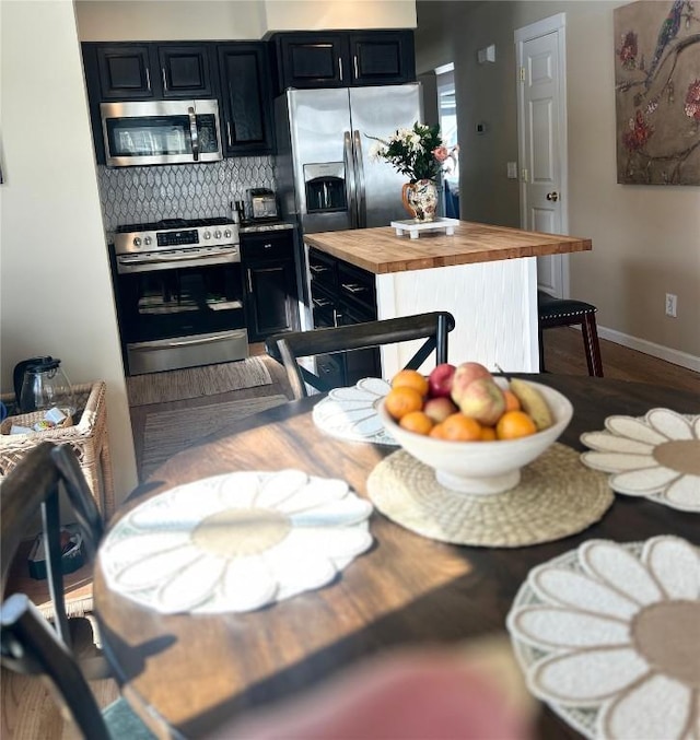 38 Huckleberry Grn, Breckenridge, CO 80424 - kitchen featuring stainless steel appliances, butcher block counters, dark cabinetry, decorative backsplash, and a kitchen island
