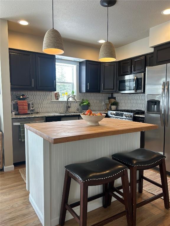 38 Huckleberry Grn, Breckenridge, CO 80424 - kitchen with butcher block counters, appliances with stainless steel finishes, backsplash, a textured ceiling, and recessed lighting