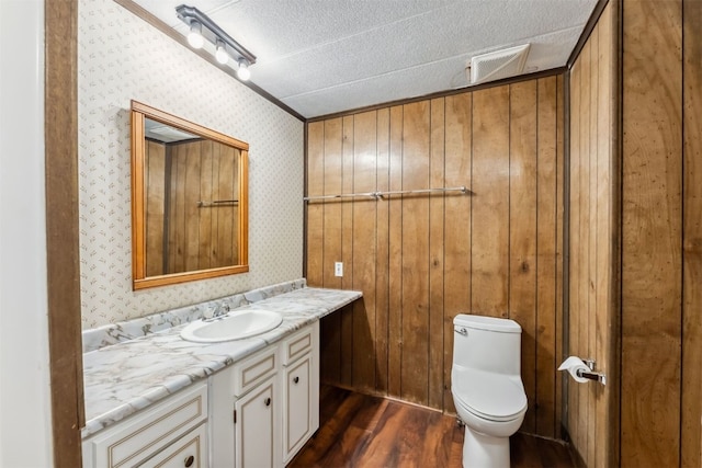 361 Lagoon Ln, Silverthorne, CO 80498 - half bath featuring wood finished floors, toilet, vanity, a textured ceiling, and wallpapered walls