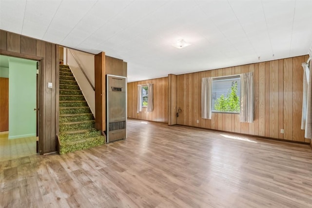 190 N Walnut St, Hayden, CO 81639 - unfurnished living room featuring a heating unit, light wood-style floors, wooden walls, and stairs