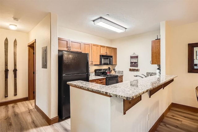 22787 US Highway 6 Unit 313, Keystone, CO 80435 - kitchen featuring black appliances, a peninsula, electric panel, and light wood-style floors