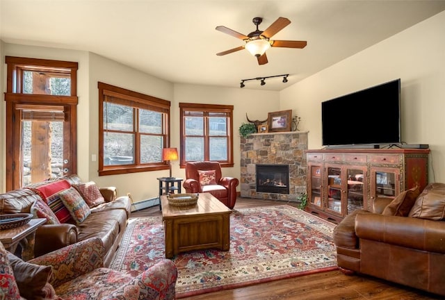 1532 Moraine Cir Unit 40, Steamboat Springs, CO 80487 - living area featuring a ceiling fan, a stone fireplace, wood finished floors, a baseboard heating unit, and track lighting