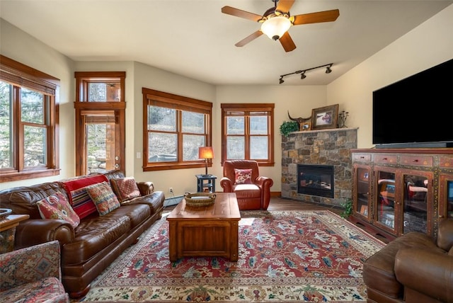 1532 Moraine Cir Unit 40, Steamboat Springs, CO 80487 - living area featuring a stone fireplace, rail lighting, wood finished floors, a baseboard radiator, and ceiling fan