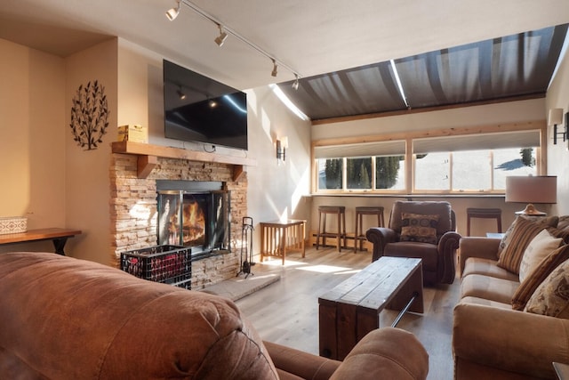 living room featuring a baseboard heating unit, a healthy amount of sunlight, a fireplace, and wood finished floors