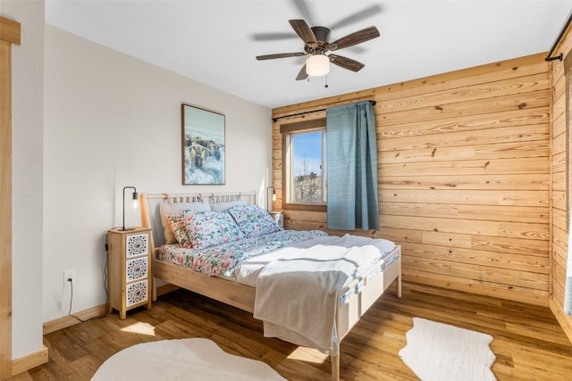 bedroom featuring wood walls, wood finished floors, and baseboards