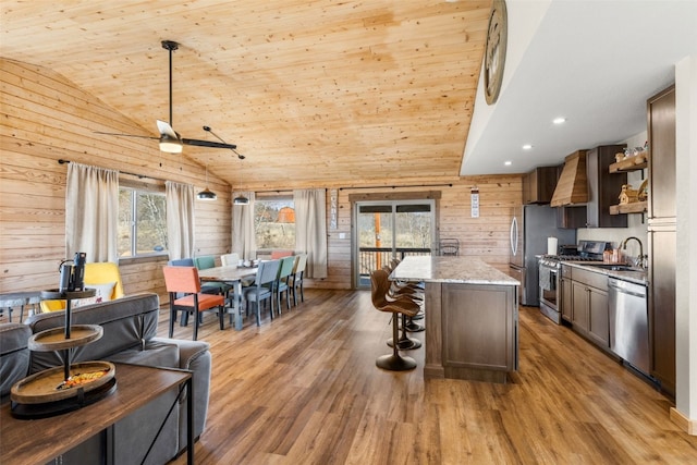 kitchen with a center island, a sink, light wood-type flooring, appliances with stainless steel finishes, and a breakfast bar area
