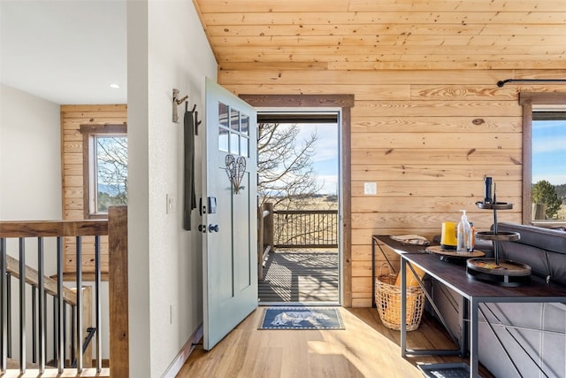 doorway to outside with a wealth of natural light, wood finished floors, wooden walls, and baseboards
