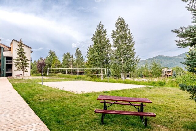 view of home's community with volleyball court, a mountain view, and a lawn