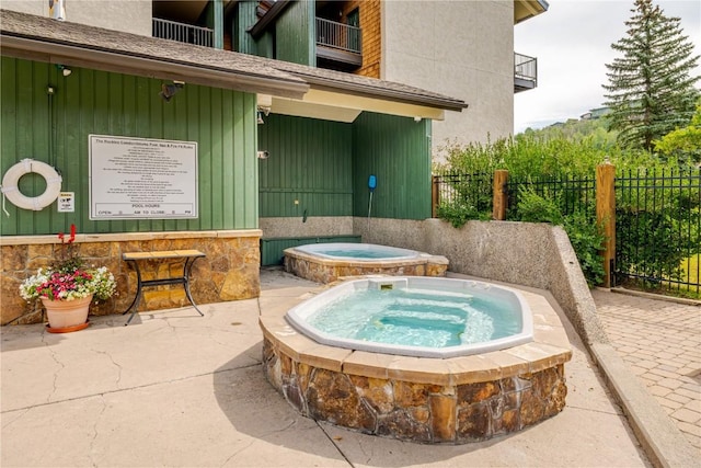 view of pool with fence and an in ground hot tub