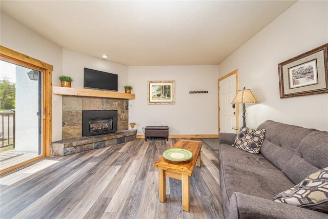 living room featuring wood finished floors, a tiled fireplace, and baseboards