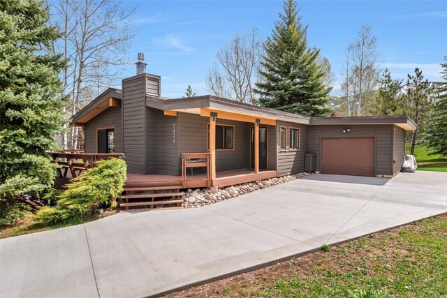 1424 Storm Peak Ln, Steamboat Springs, CO 80487 - modern home featuring an attached garage, concrete driveway, and a chimney