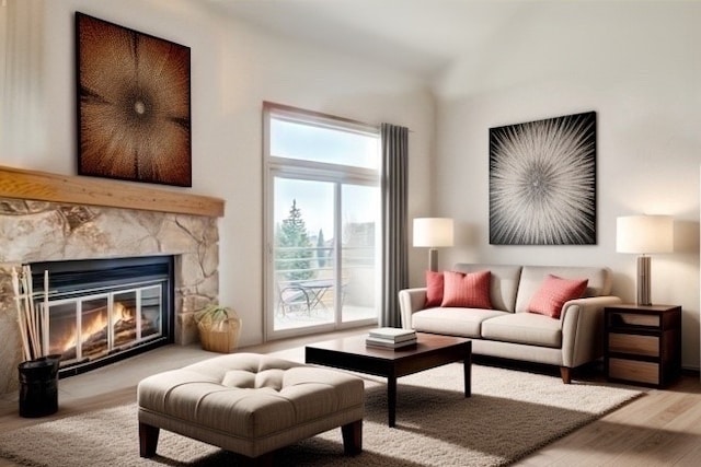 living area featuring wood finished floors and a stone fireplace