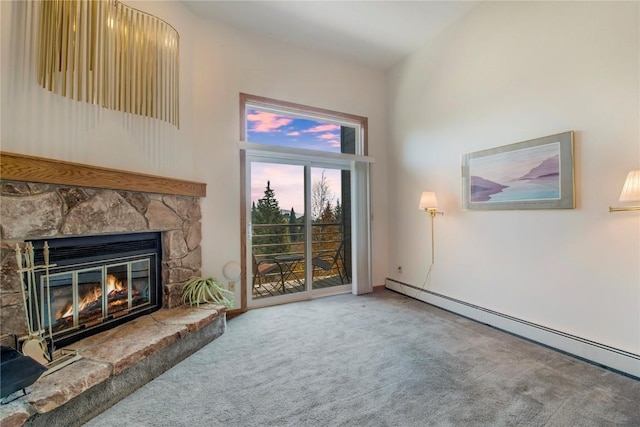 unfurnished living room with baseboard heating, carpet floors, a towering ceiling, and a fireplace