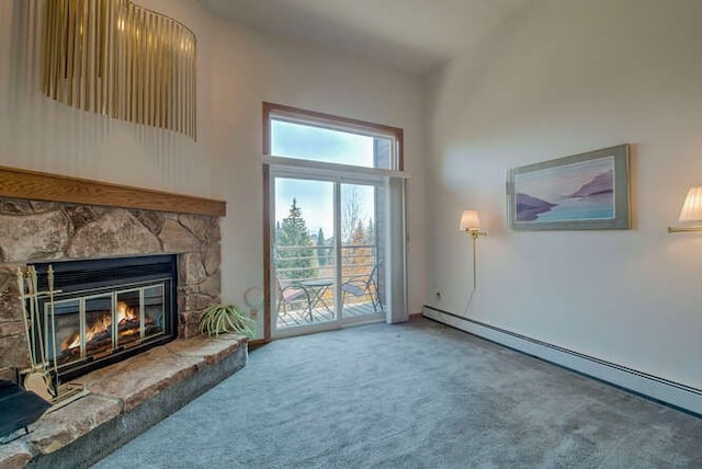 unfurnished living room featuring a baseboard heating unit, carpet, a towering ceiling, and a fireplace