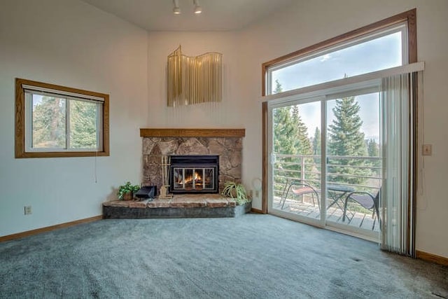 unfurnished living room with a stone fireplace, carpet flooring, and baseboards