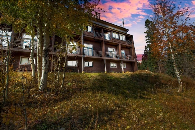 back of property at dusk featuring a balcony