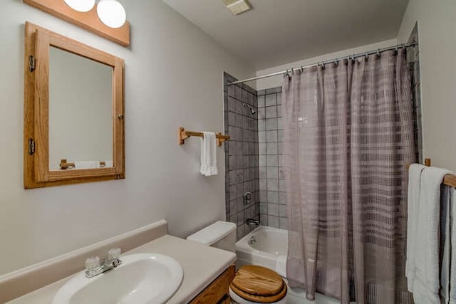 bathroom with shower / bath combo with shower curtain, toilet, and vanity