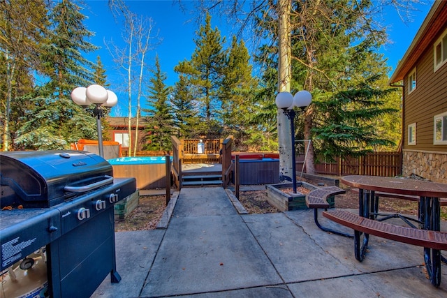 view of patio with fence, a wooden deck, a hot tub, and area for grilling