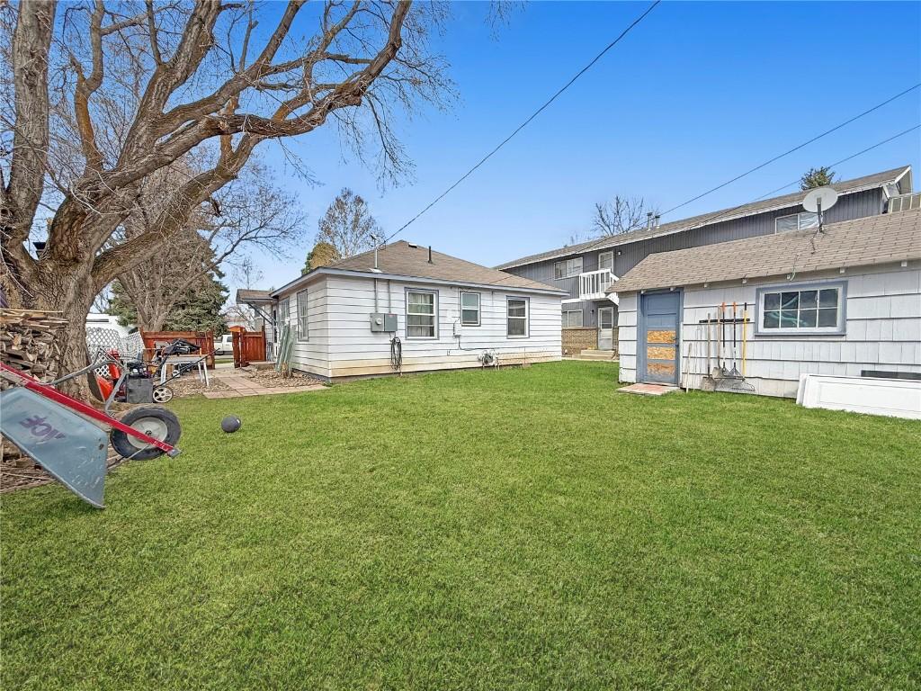 back of property with fence, a yard, and a shingled roof