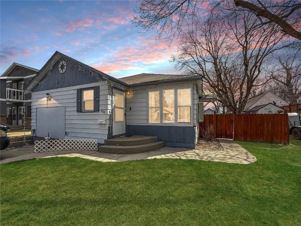 back of property featuring a lawn and fence