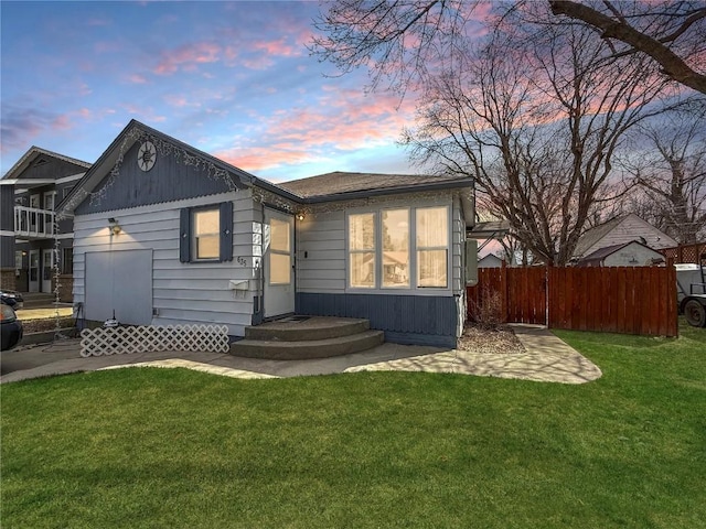 back of property featuring a lawn and fence
