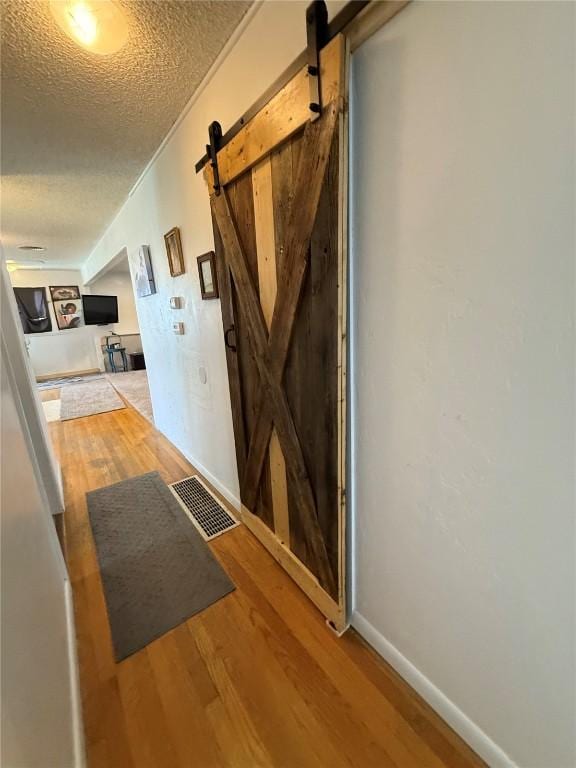 635 School St, Craig, CO 81625 - hallway with a barn door, a textured ceiling, wood finished floors, and baseboards