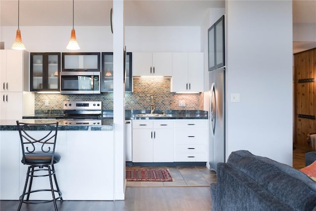 72 Corinthian Cir Unit 303, Dillon, CO 80435 - kitchen featuring stainless steel appliances, tasteful backsplash, glass insert cabinets, and dark countertops