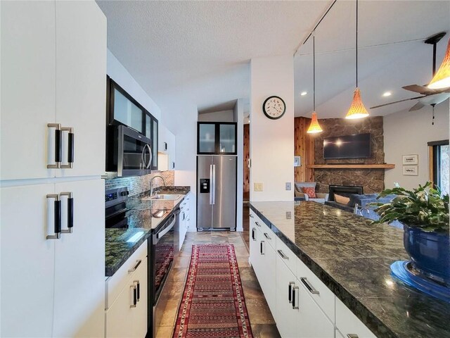 72 Corinthian Cir Unit 303, Dillon, CO 80435 - kitchen with stainless steel appliances, decorative backsplash, a stone fireplace, pendant lighting, and white cabinets