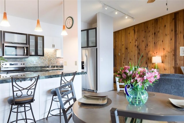 72 Corinthian Cir Unit 303, Dillon, CO 80435 - kitchen with appliances with stainless steel finishes, track lighting, tasteful backsplash, wooden walls, and a breakfast bar area