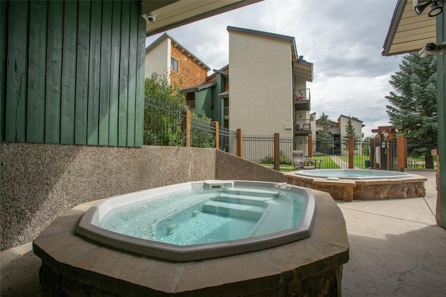 view of swimming pool featuring an in ground hot tub and fence