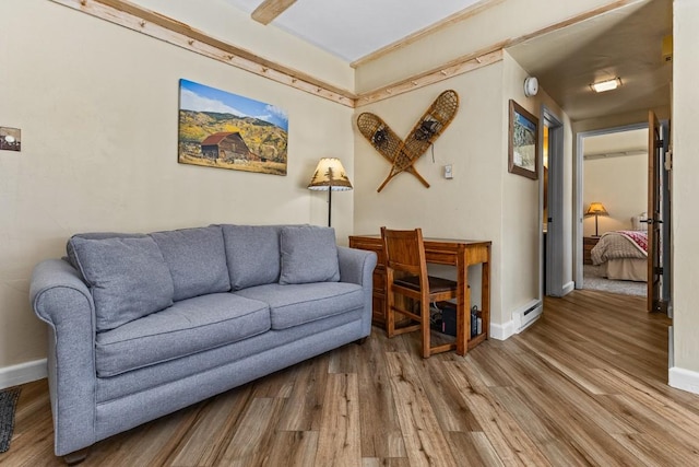 living area featuring baseboards, wood finished floors, and a baseboard radiator