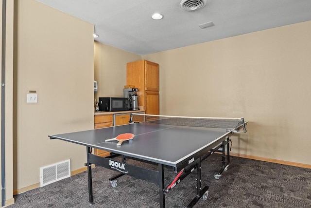 game room featuring baseboards, dark colored carpet, and visible vents