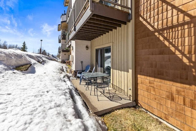 snow covered patio featuring a balcony