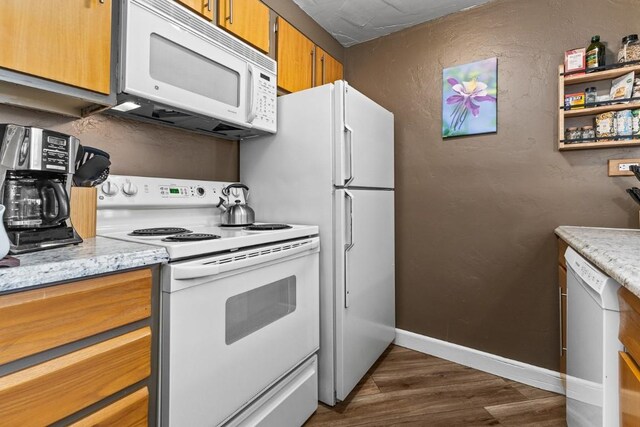 kitchen featuring brown cabinetry, baseboards, dark wood-style flooring, and white appliances