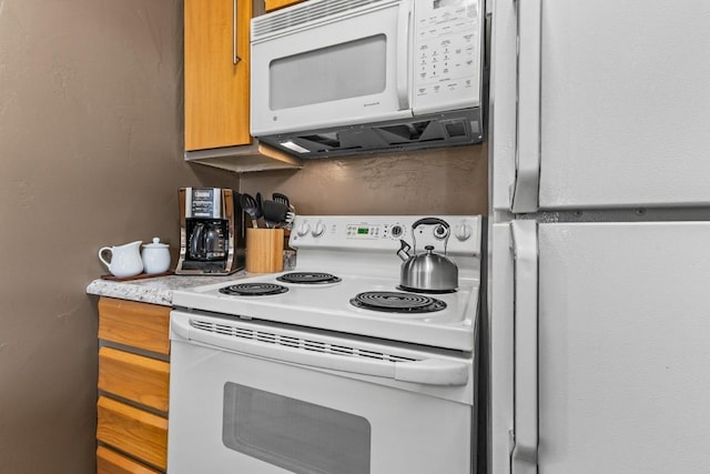 kitchen with brown cabinets, light countertops, and white appliances