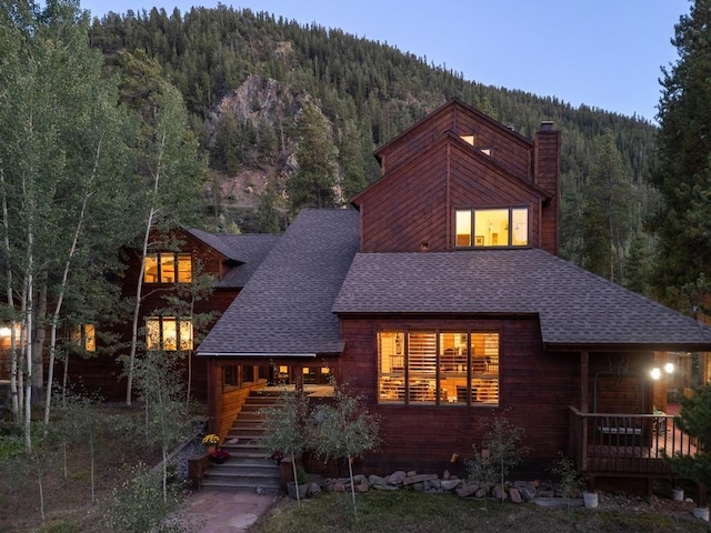 82 Lenawee Ln, Keystone, CO 80435 - view of front of house with a view of trees, roof with shingles, a chimney, covered porch, and stairway