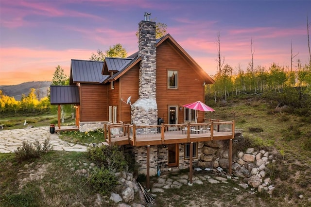 51193 Smith Creek Park Rd, Steamboat Springs, CO 80487 - back of house featuring stone siding, a standing seam roof, a wooden deck, a chimney, and metal roof