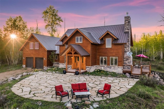 51193 Smith Creek Park Rd, Steamboat Springs, CO 80487 - rear view of property with a standing seam roof, a deck, a chimney, stone siding, and metal roof