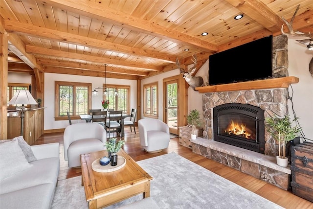 51193 Smith Creek Park Rd, Steamboat Springs, CO 80487 - living room featuring beamed ceiling, a stone fireplace, wood ceiling, wood finished floors, and baseboards