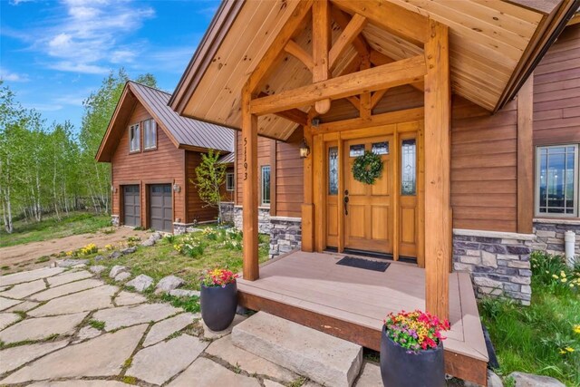 51193 Smith Creek Park Rd, Steamboat Springs, CO 80487 - view of exterior entry featuring stone siding, a garage, and metal roof