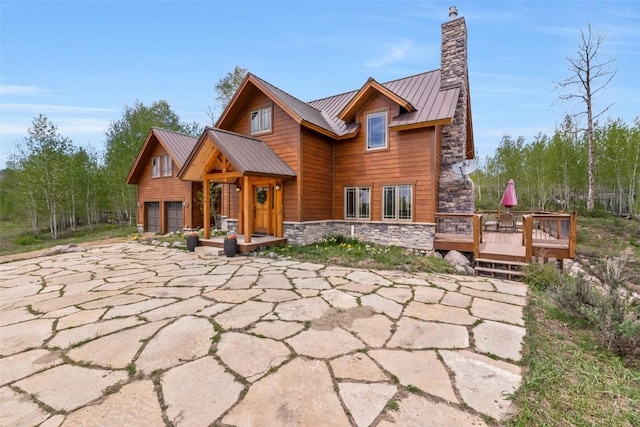 51193 Smith Creek Park Rd, Steamboat Springs, CO 80487 - rustic home featuring stone siding, a chimney, a standing seam roof, a wooden deck, and metal roof