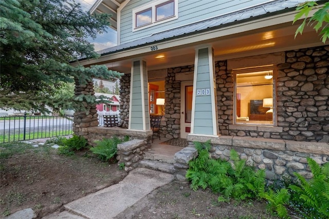 203 Spruce St, Steamboat Springs, CO 80487 - property entrance featuring covered porch, metal roof, fence, and stone siding