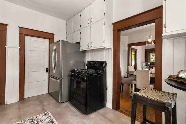 203 Spruce St, Steamboat Springs, CO 80487 - kitchen featuring black range with gas stovetop, white cabinets, freestanding refrigerator, and finished concrete flooring