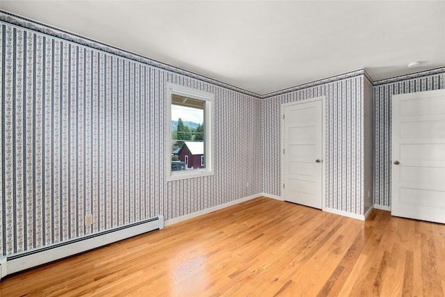 203 Spruce St, Steamboat Springs, CO 80487 - unfurnished bedroom featuring a baseboard radiator, wood finished floors, wallpapered walls, and baseboards