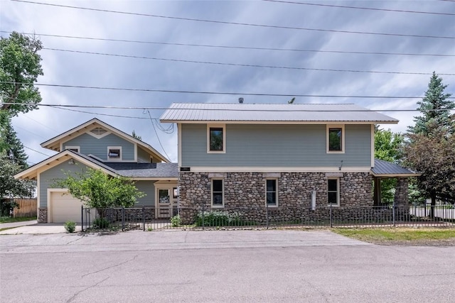203 Spruce St, Steamboat Springs, CO 80487 - view of front of house with fence, stone siding, an attached garage, concrete driveway, and metal roof
