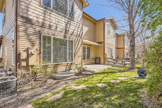 back of house featuring central AC unit, a patio, and a lawn