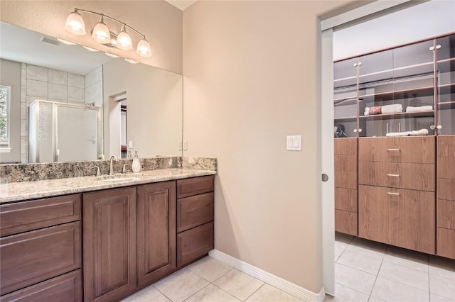 bathroom featuring tile patterned floors, a shower stall, vanity, and baseboards